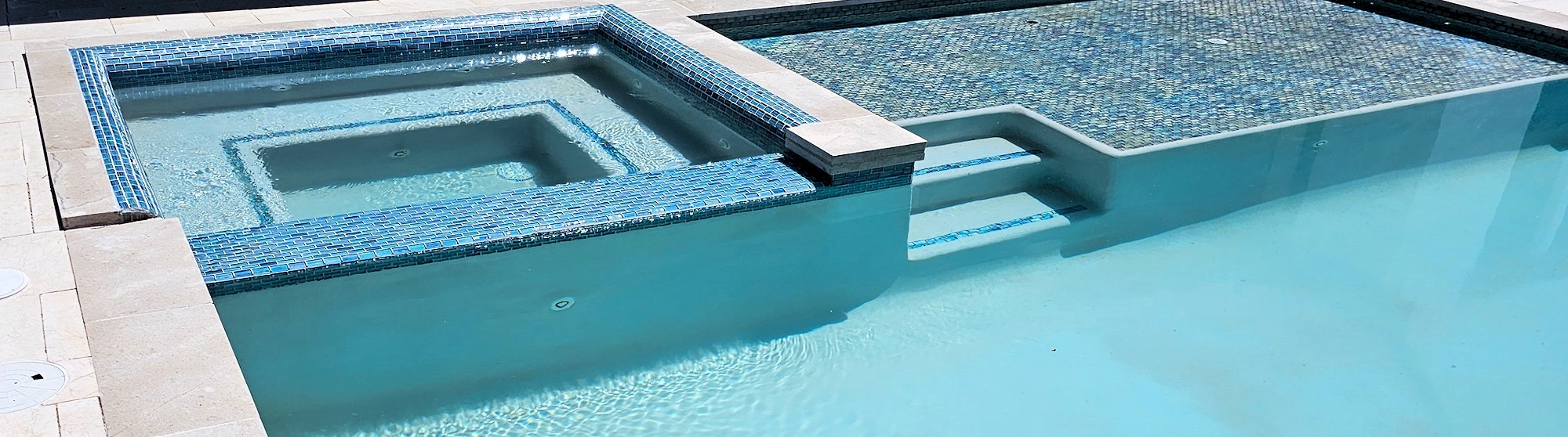 Wide angle shot of a residential pool with wading pool and oasis.
